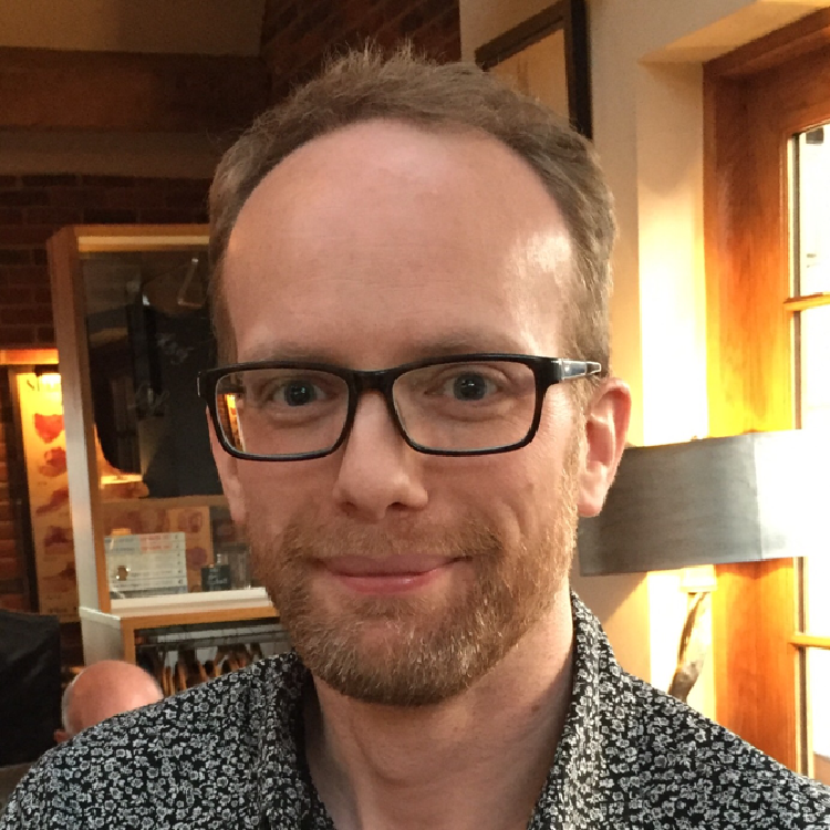 Headshot of Jon smiling to camera with a flowery shirt.